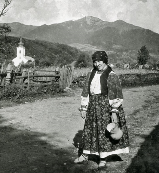 "A Living Lens": A Jewish woman in a Carpathian mountain town posing on a country road, water pitcher in hand
